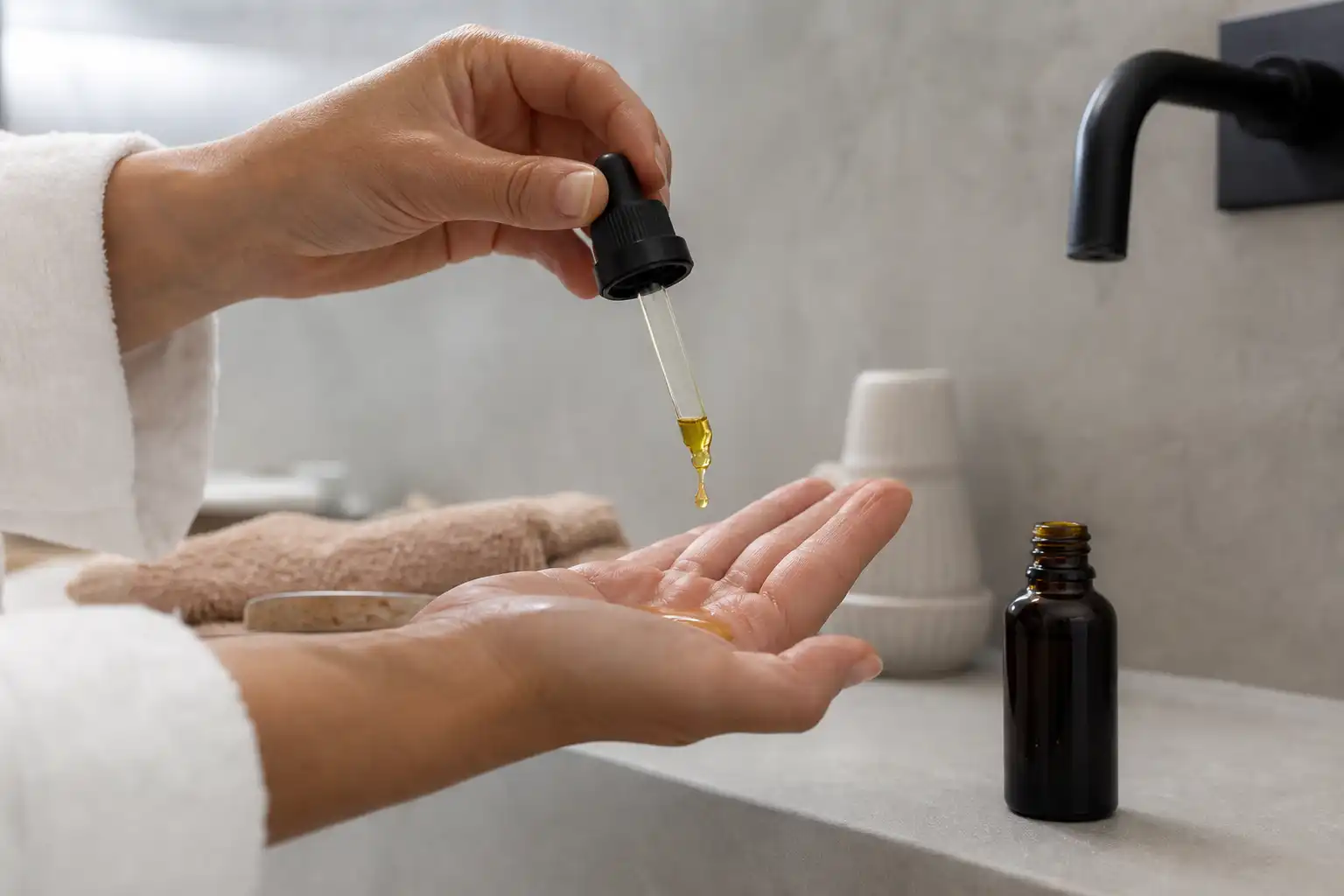 Des mains dosent quelque chose, autour d'huile cbd effets, dans une salle de bain.